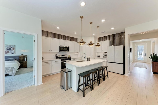 3129 61st Ter E, Ellenton, FL 34222 - kitchen featuring appliances with stainless steel finishes, a sink, a breakfast bar area, white cabinetry, and light wood-type flooring