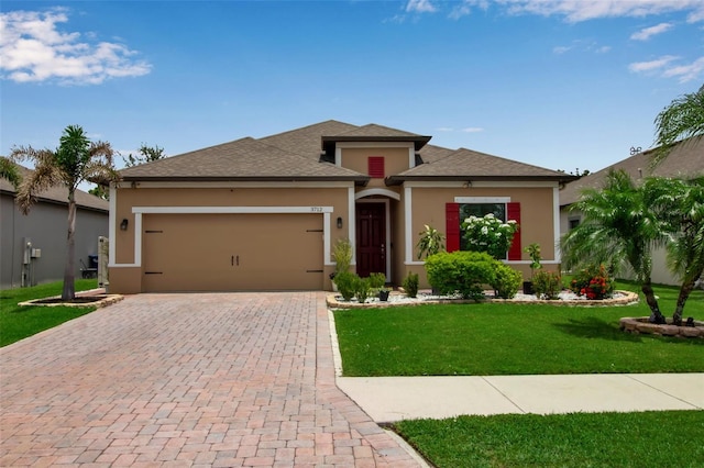 3712 76th St E, Palmetto, FL 34221 - view of front facade featuring stucco siding, a garage, decorative driveway, a front lawn, and a shingled roof