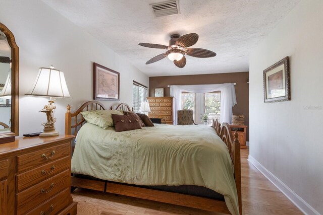 715 Fontana Ln, Bradenton, FL 34209 - bedroom with light wood-style floors, baseboards, a ceiling fan, and a textured ceiling
