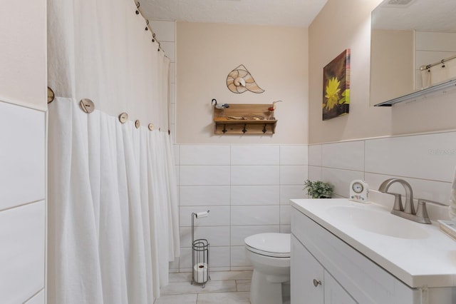 715 Fontana Ln, Bradenton, FL 34209 - bathroom featuring tile walls, vanity, toilet, tile patterned floors, and a wainscoted wall