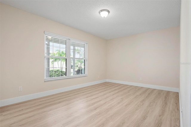 4472 Calle Serena, Sarasota, FL 34238 - empty room with light wood finished floors, a textured ceiling, and baseboards