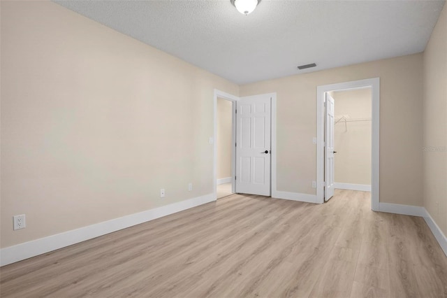 4472 Calle Serena, Sarasota, FL 34238 - unfurnished bedroom featuring light wood finished floors, baseboards, a closet, a spacious closet, and a textured ceiling