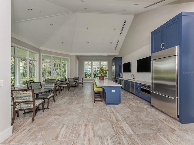 12682 Shimmering Oak Cir, Venice, FL 34293 - kitchen featuring stainless steel appliances, blue cabinets, light countertops, a breakfast bar area, and high vaulted ceiling