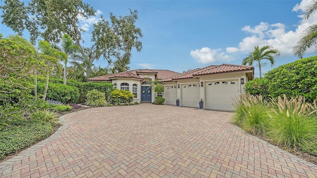 1864 Goldenrod St, Sarasota, FL 34239 - mediterranean / spanish house featuring a garage, decorative driveway, stucco siding, and a tiled roof