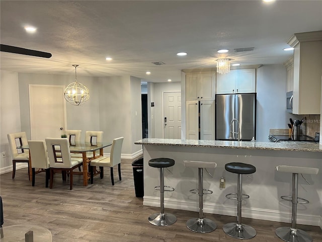 4441 Groveland Ave, Sarasota, FL 34231 - kitchen with stainless steel appliances, baseboards, a peninsula, light stone countertops, and a breakfast bar area