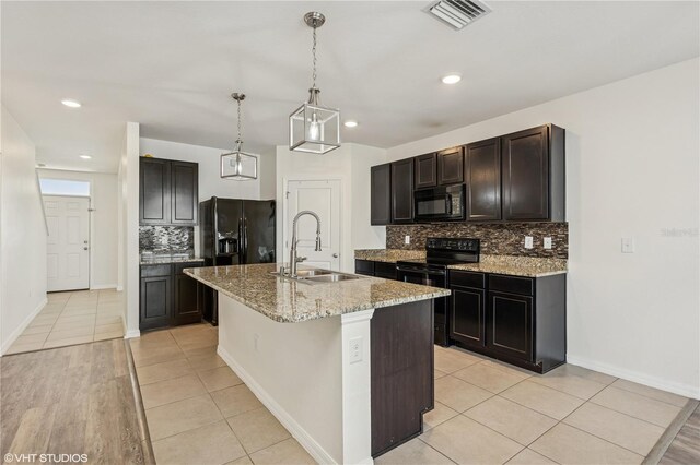 4005 Willow Branch Pl, Palmetto, FL 34221 - kitchen featuring black appliances, a sink, tasteful backsplash, light stone counters, and a center island with sink