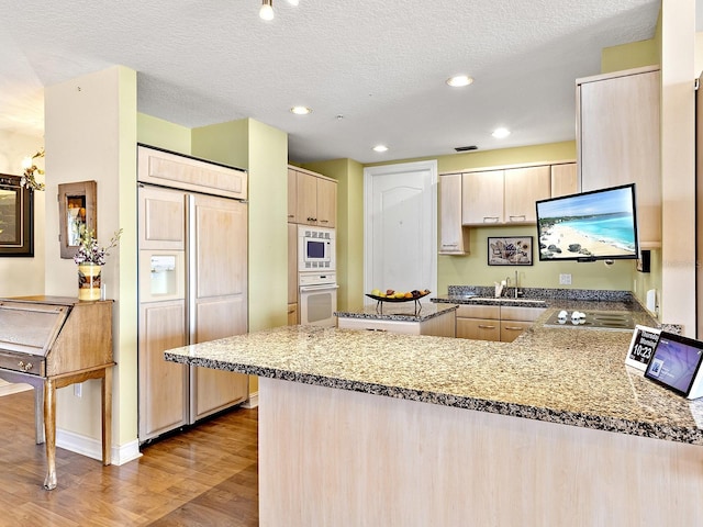 1233 N Gulfstream Ave Unit 401, Sarasota, FL 34236 - kitchen with built in appliances, a sink, a peninsula, light brown cabinetry, and wood finished floors