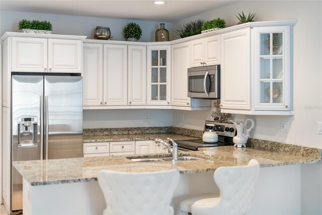 525 N Orange Ave Unit 302, Sarasota, FL 34236 - kitchen with stainless steel appliances, a sink, glass insert cabinets, light stone counters, and a kitchen bar