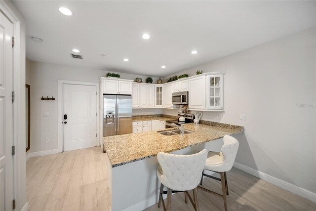 525 N Orange Ave Unit 302, Sarasota, FL 34236 - kitchen featuring stainless steel appliances, a peninsula, baseboards, a kitchen breakfast bar, and light wood finished floors