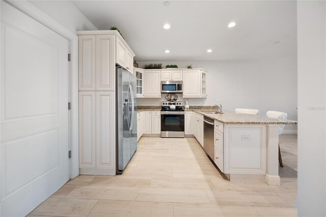 525 N Orange Ave Unit 302, Sarasota, FL 34236 - kitchen with appliances with stainless steel finishes, a peninsula, a kitchen breakfast bar, light stone countertops, and recessed lighting