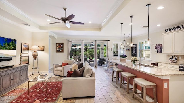 11625 Parrotfish St, Venice, FL 34292 - living room featuring a ceiling fan, plenty of natural light, a raised ceiling, ornamental molding, and light wood-style floors