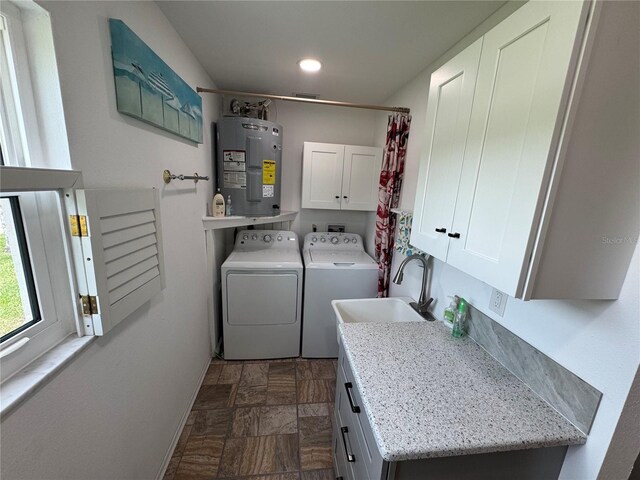 3752 Collins St Unit 508, Sarasota, FL 34232 - washroom featuring electric water heater, cabinet space, washing machine and dryer, dark stone finish flooring, and baseboards