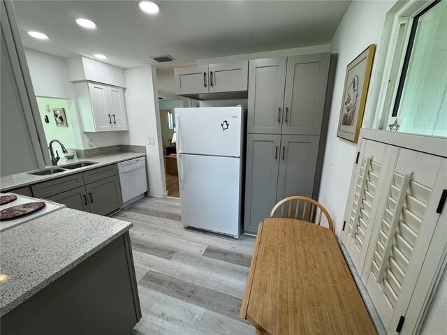3752 Collins St Unit 508, Sarasota, FL 34232 - kitchen featuring white appliances, a sink, gray cabinetry, light wood-type flooring, and light stone counters