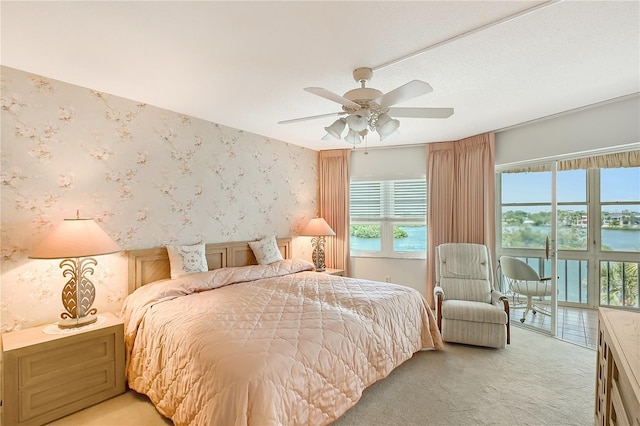 1350 N Portofino Dr Unit 402, Sarasota, FL 34242 - bedroom featuring wallpapered walls, light colored carpet, access to outside, a ceiling fan, and a water view