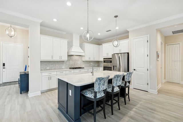 13606 Deep Blue Pl, Bradenton, FL 34211 - kitchen with custom range hood, light wood finished floors, a kitchen island with sink, white cabinetry, and recessed lighting