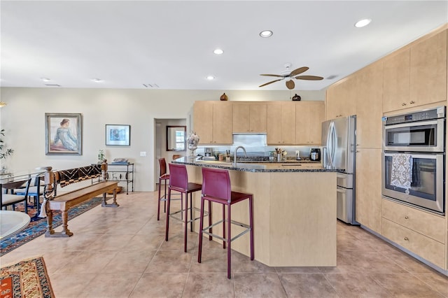 105 Inlets Blvd Unit 105, Nokomis, FL 34275 - kitchen with light brown cabinets, stainless steel appliances, dark stone countertops, a kitchen breakfast bar, and ceiling fan