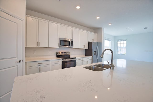 17715 Boracay Ct Unit 202, Venice, FL 34293 - kitchen featuring appliances with stainless steel finishes, a sink, recessed lighting, white cabinets, and light stone counters