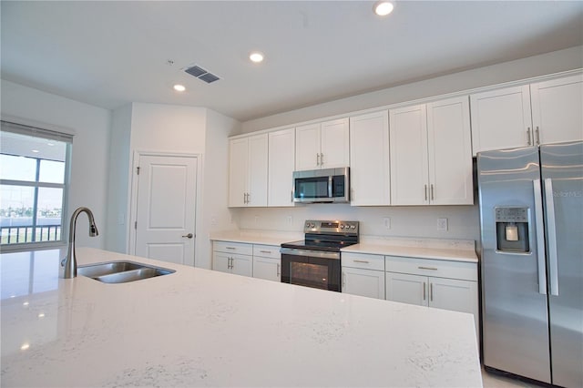 17715 Boracay Ct Unit 202, Venice, FL 34293 - kitchen with appliances with stainless steel finishes, a sink, white cabinets, recessed lighting, and light stone counters