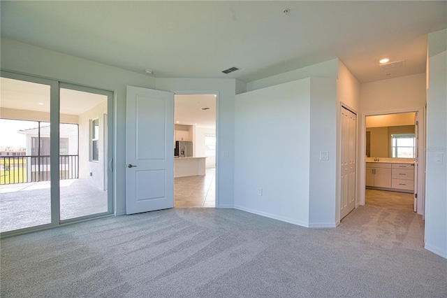 17715 Boracay Ct Unit 202, Venice, FL 34293 - unfurnished bedroom featuring light colored carpet, access to outside, stainless steel fridge, baseboards, and recessed lighting