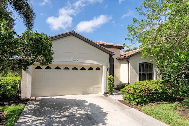 8078 Stirling Falls Cir, Sarasota, FL 34243 - mediterranean / spanish-style house featuring concrete driveway, stucco siding, a tile roof, and an attached garage