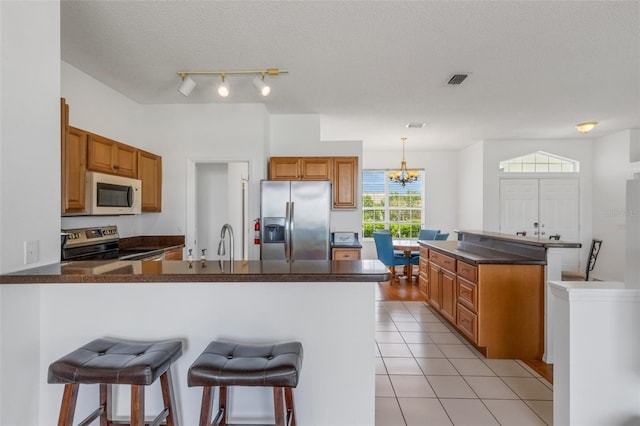 9402 71st Ave E, Palmetto, FL 34221 - kitchen with stainless steel fridge, white microwave, range with electric cooktop, a peninsula, and dark countertops