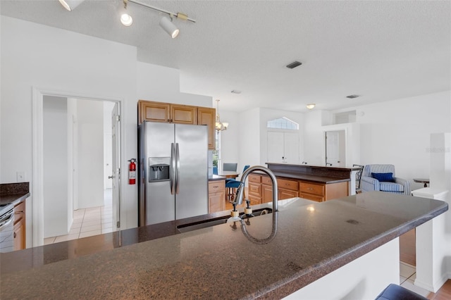 9402 71st Ave E, Palmetto, FL 34221 - kitchen featuring stainless steel refrigerator with ice dispenser, a sink, light tile patterned flooring, and dark stone counters