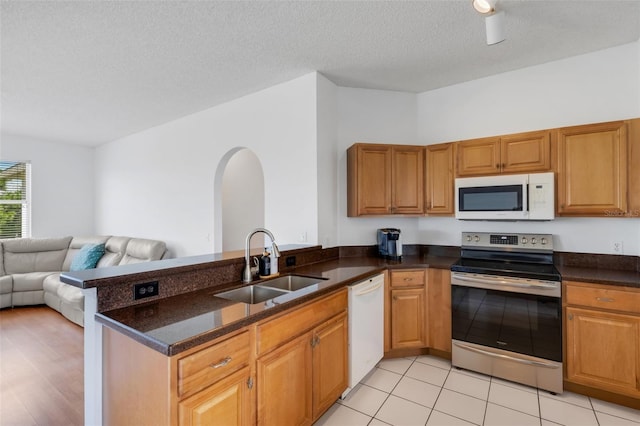 9402 71st Ave E, Palmetto, FL 34221 - kitchen with white appliances, arched walkways, a sink, open floor plan, and a peninsula