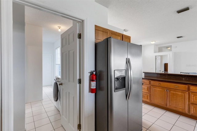 9402 71st Ave E, Palmetto, FL 34221 - kitchen with stainless steel refrigerator with ice dispenser, light tile patterned flooring, brown cabinets, and dark countertops