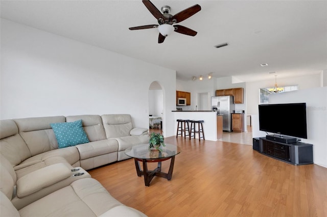 9402 71st Ave E, Palmetto, FL 34221 - living room featuring a ceiling fan, arched walkways, light wood-style flooring, and a chandelier