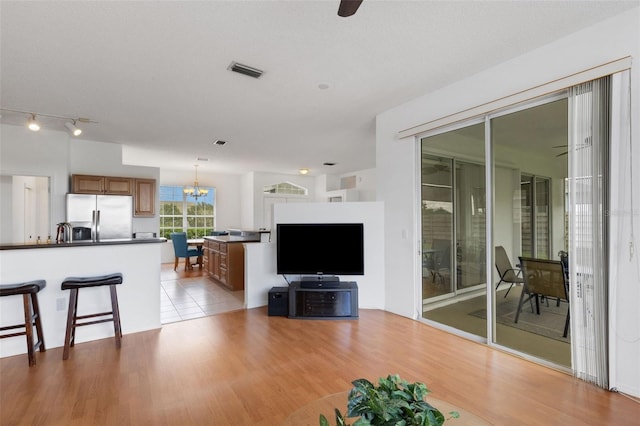 9402 71st Ave E, Palmetto, FL 34221 - living room with light wood-style flooring, a ceiling fan, and a chandelier