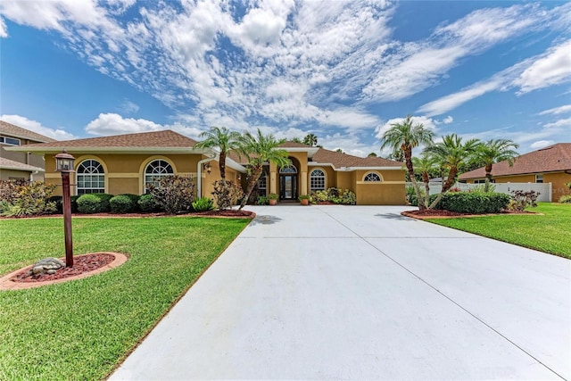 5359 90th Avenue Cir E, Parrish, FL 34219 - mediterranean / spanish-style home with stucco siding, curved driveway, a front yard, and an attached garage