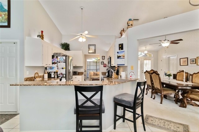 6405 Alesheba Ln, Sarasota, FL 34240 - kitchen featuring a ceiling fan, light stone countertops, stainless steel fridge, a peninsula, and vaulted ceiling