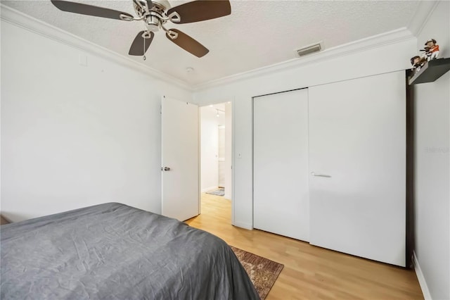 6860 Whitman Ct Unit 32B, Sarasota, FL 34243 - bedroom with ornamental molding, light wood-type flooring, a textured ceiling, ceiling fan, and a closet