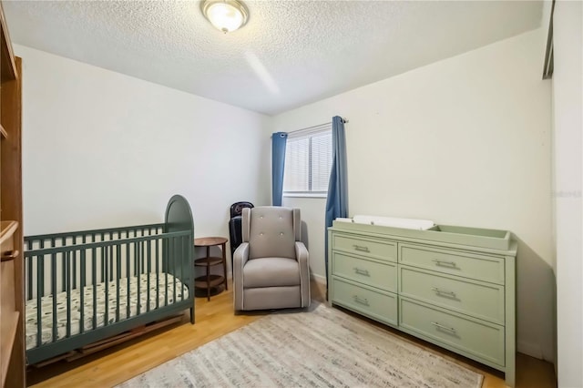 6860 Whitman Ct Unit 32B, Sarasota, FL 34243 - bedroom with a textured ceiling, light wood-style floors, and a crib