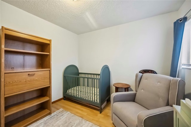 6860 Whitman Ct Unit 32B, Sarasota, FL 34243 - bedroom featuring light wood-style flooring, a crib, and a textured ceiling