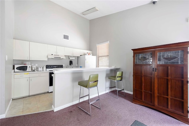 6860 Whitman Ct Unit 32B, Sarasota, FL 34243 - kitchen featuring white appliances, under cabinet range hood, a towering ceiling, light carpet, and white cabinetry