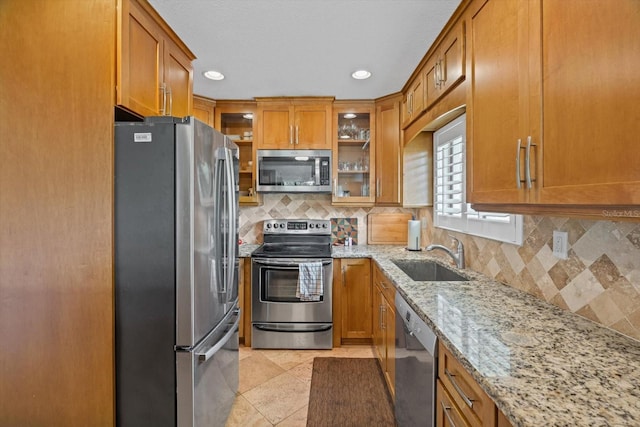3500 El Conquistador Pkwy Unit 132, Bradenton, FL 34210 - kitchen with stainless steel appliances, a sink, brown cabinetry, light stone counters, and recessed lighting