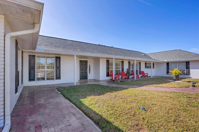 2005 21st St W, Palmetto, FL 34221 - back of property with a lawn, brick siding, a shingled roof, and a patio area