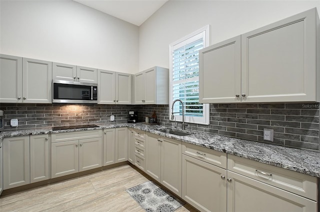 22343 Panther Loop, Bradenton, FL 34202 - kitchen featuring stainless steel microwave, black electric stovetop, decorative backsplash, and light stone countertops