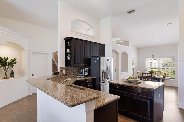 12031 Longview Lake Cir, Lakewood Ranch, FL 34211 - kitchen with stainless steel fridge, decorative backsplash, a sink, high vaulted ceiling, and a kitchen island