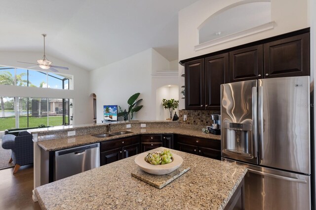 12031 Longview Lake Cir, Lakewood Ranch, FL 34211 - kitchen featuring stainless steel appliances, a sink, vaulted ceiling, a peninsula, and light stone countertops