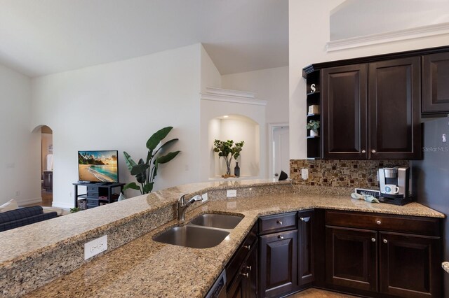 12031 Longview Lake Cir, Lakewood Ranch, FL 34211 - kitchen with a sink, arched walkways, light stone counters, dark brown cabinets, and tasteful backsplash