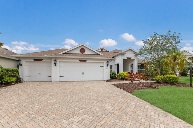12031 Longview Lake Cir, Lakewood Ranch, FL 34211 - view of front of house with decorative driveway, an attached garage, stucco siding, and a front lawn