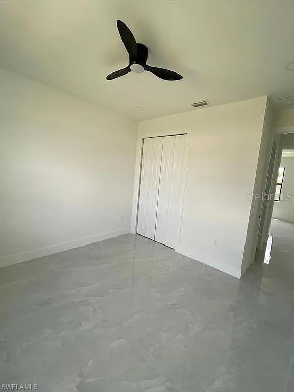 3017 4th St W, Lehigh Acres, FL 33971 - unfurnished bedroom with baseboards, concrete flooring, a closet, and a ceiling fan
