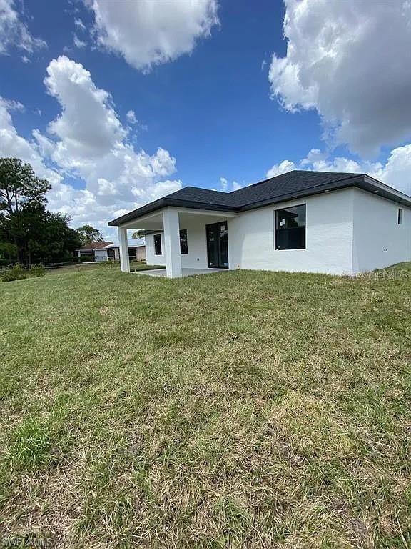 3017 4th St W, Lehigh Acres, FL 33971 - back of property featuring a lawn and stucco siding