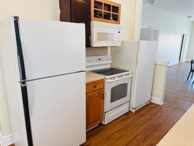 1412 12th Ave W, Bradenton, FL 34205 - kitchen with white appliances, wood finished floors, light countertops, brown cabinets, and baseboards