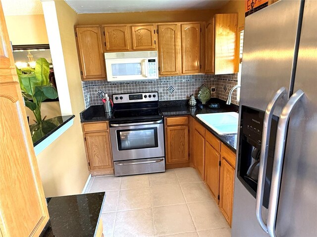 390 301st Blvd W Unit 2C, Bradenton, FL 34205 - kitchen with stainless steel appliances, decorative backsplash, light tile patterned floors, and brown cabinetry
