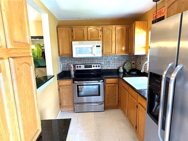 390 301st Blvd W Unit 2C, Bradenton, FL 34205 - kitchen featuring appliances with stainless steel finishes, dark countertops, light tile patterned floors, and tasteful backsplash