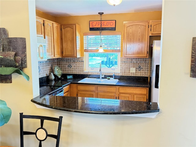 390 301st Blvd W Unit 2C, Bradenton, FL 34205 - kitchen with white microwave, backsplash, hanging light fixtures, and a peninsula