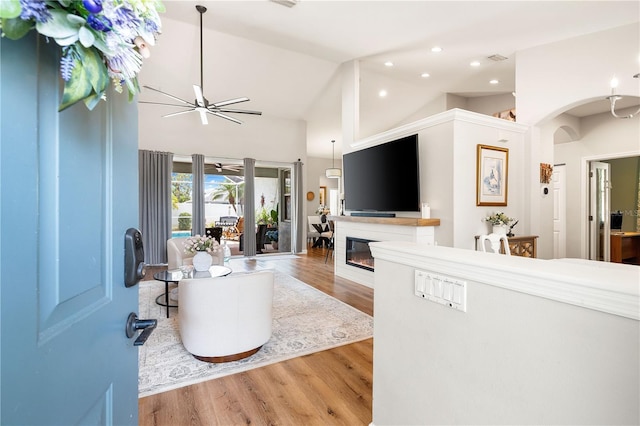 6750 64th Ter E, Bradenton, FL 34203 - living area with ceiling fan, wood finished floors, a glass covered fireplace, arched walkways, and high vaulted ceiling